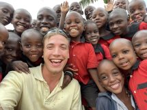 Austin Foe poses with Ugandan children at the mission construction site.